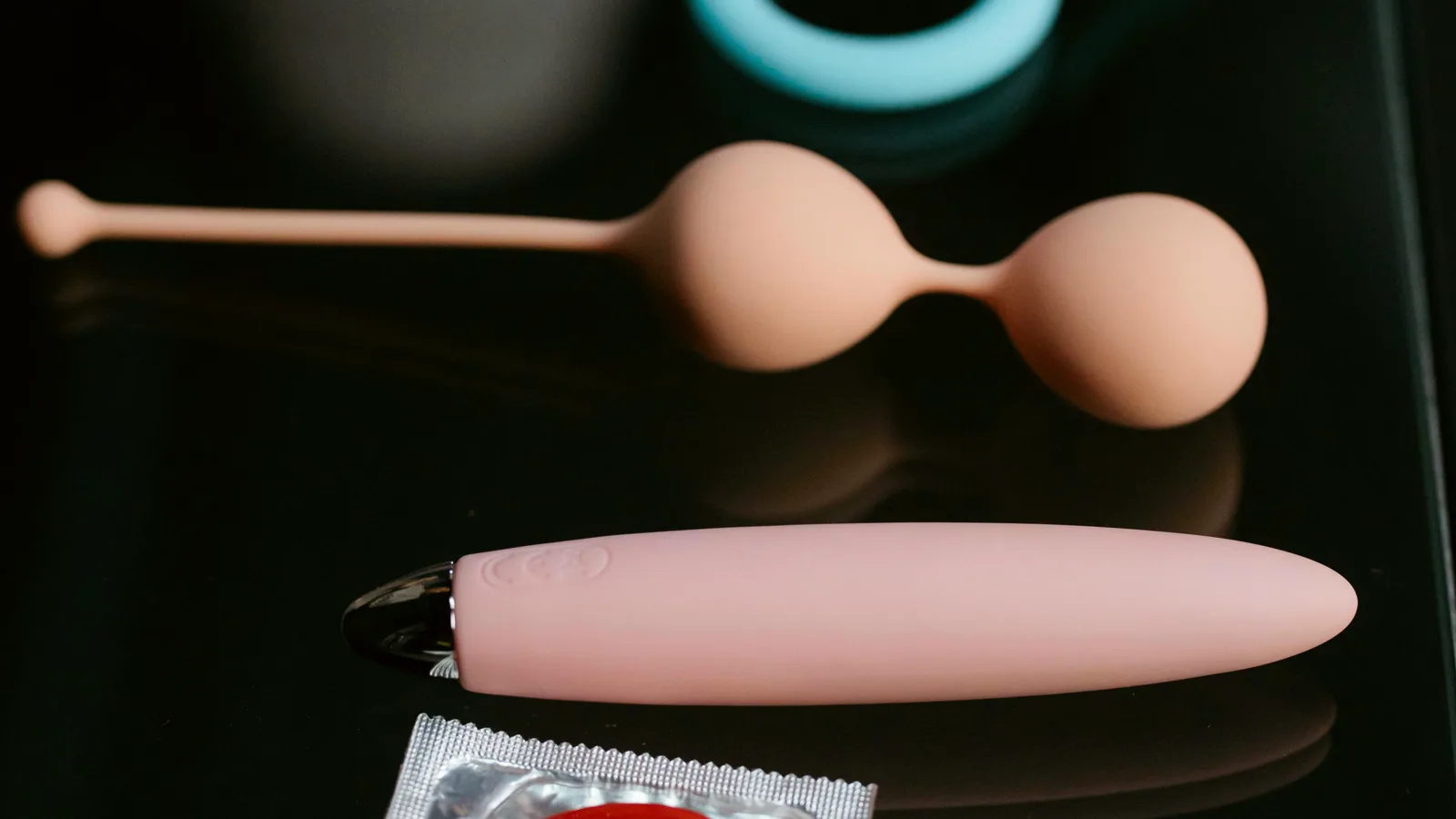 Bolas chinas, un vibrador de bala y un preservativo sobre una superficie negra